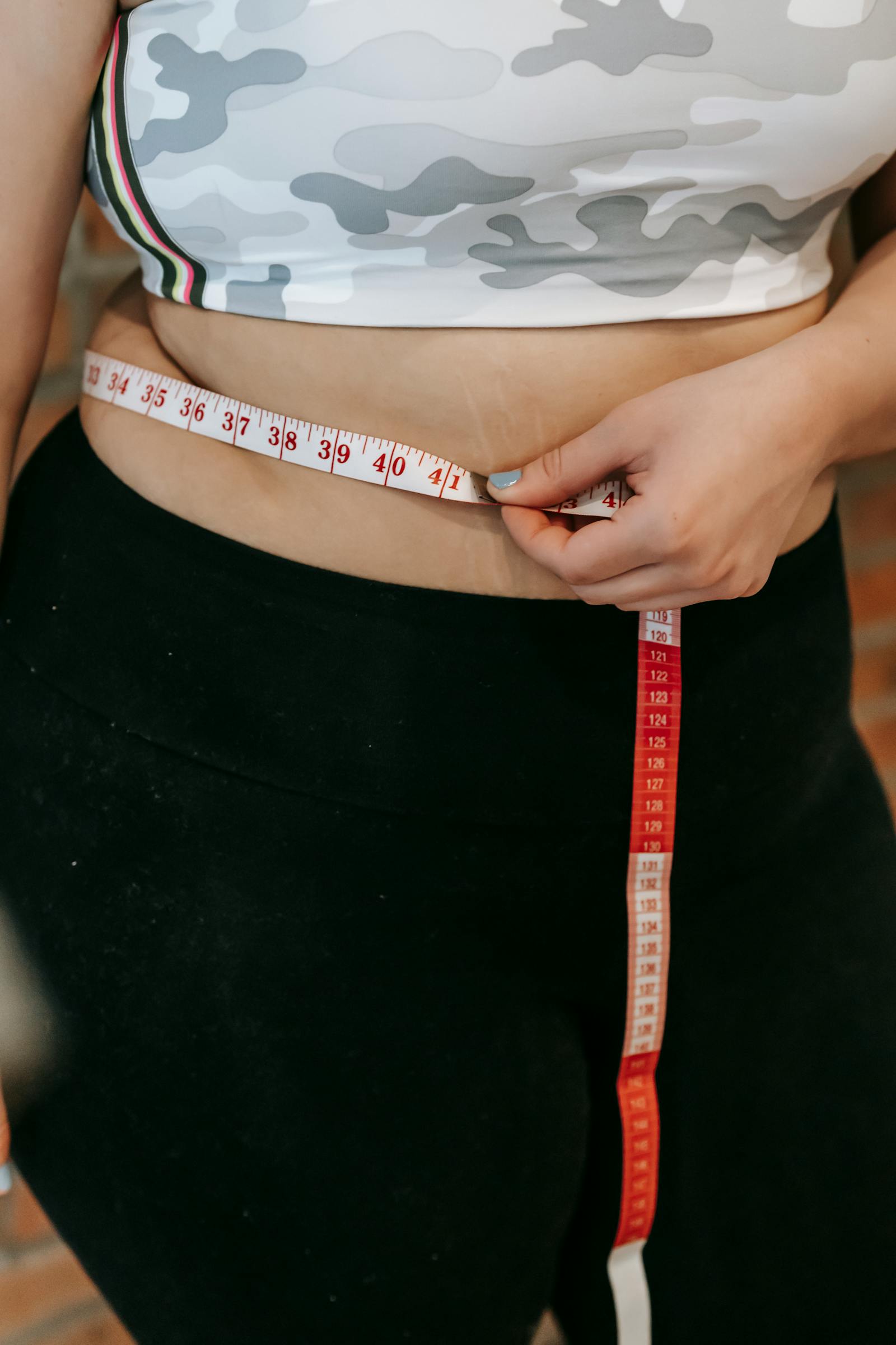 Middle-aged woman measuring waist in activewear for a menopause belly fat article
